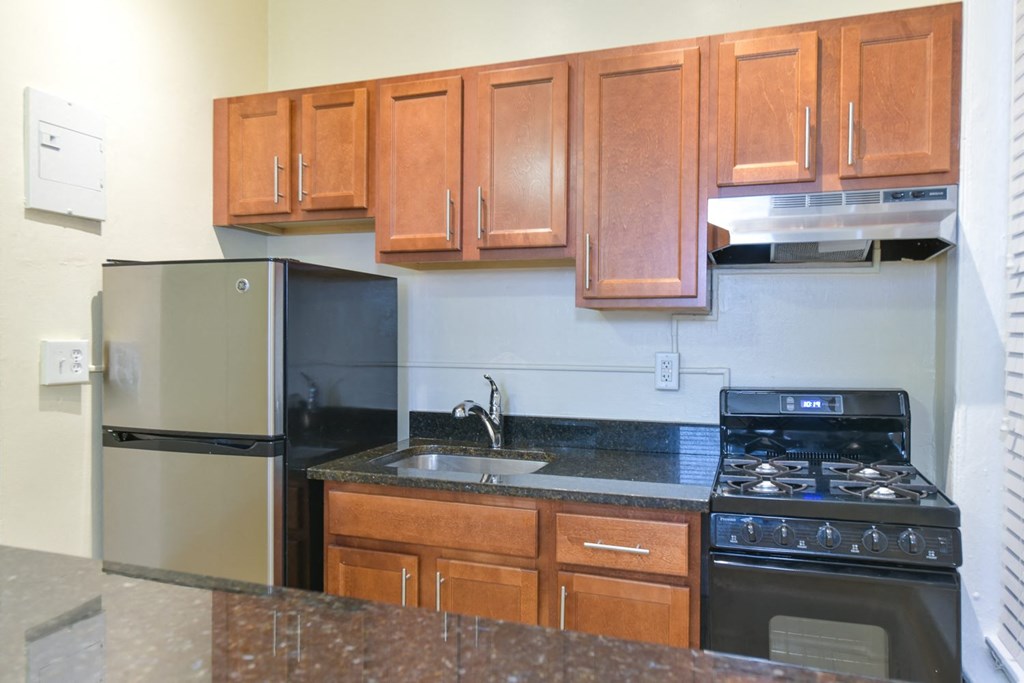 kitchen with wood cabinetry, gas stove, and granite countertops at dupont apartments in washington dc
