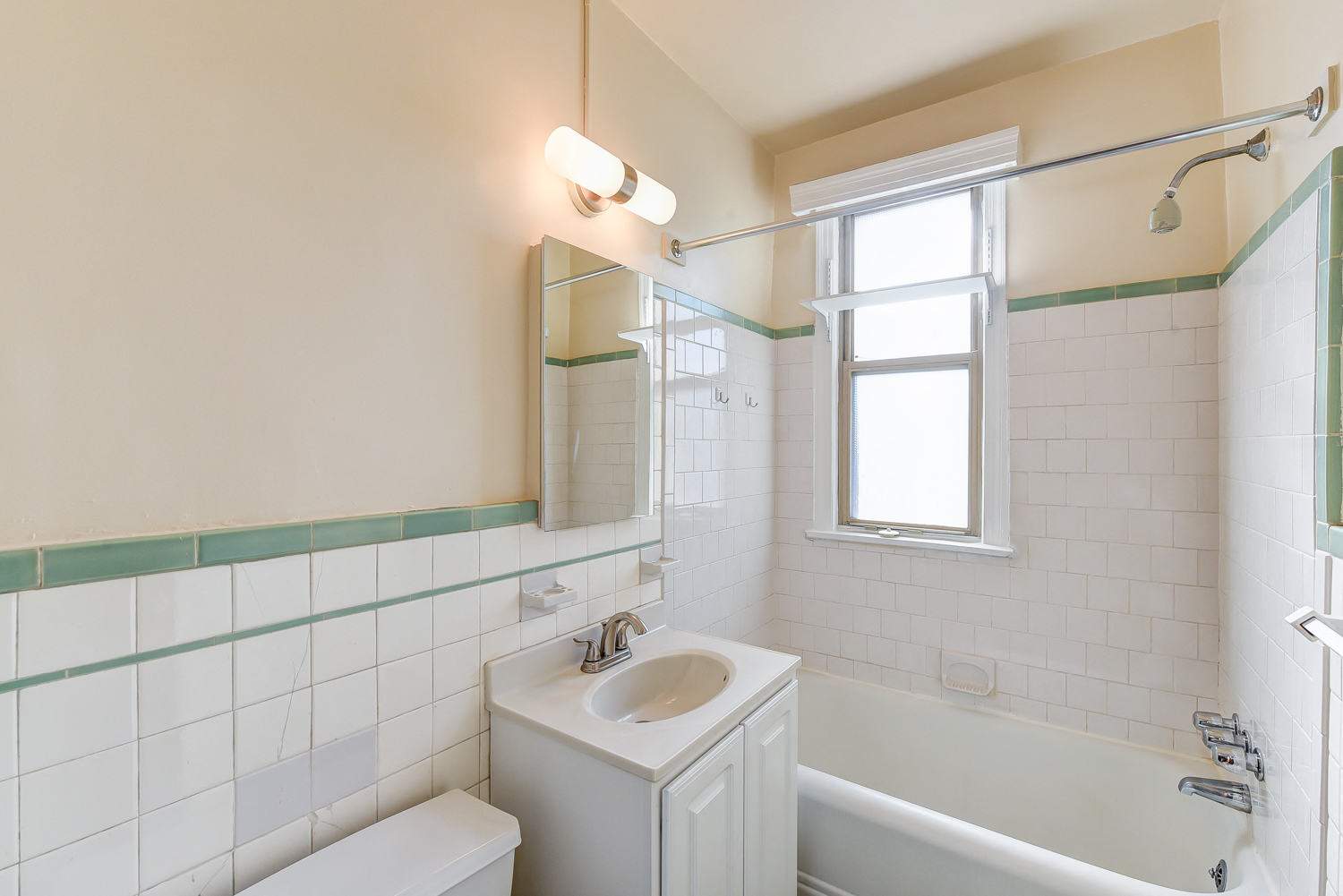 bathroom with toilet, vanity, tub, and window at eddystone apartments in washington dc