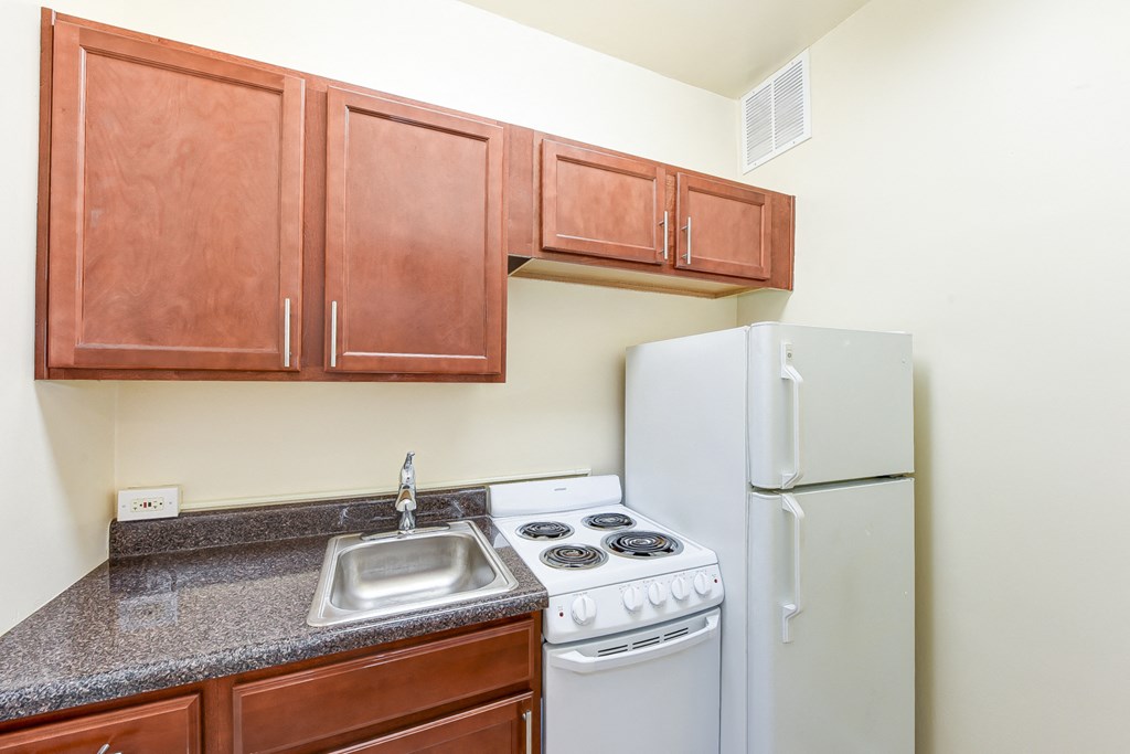 kitchen with wood cabinetry, electric range and refrigerator at eddystone apartments in washington dc