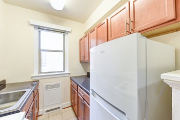 kitchen with wood cabinetry, electric range, refrigerator, and window at eddystone apartments in washington dc