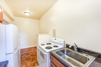 kitchen with wood cabinetry, electric range and refrigerator at eddystone apartments in washington dc