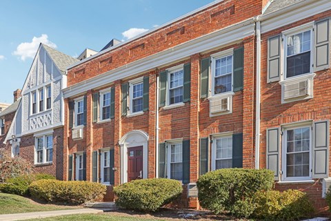 A red brick building with green shutters and a white door.