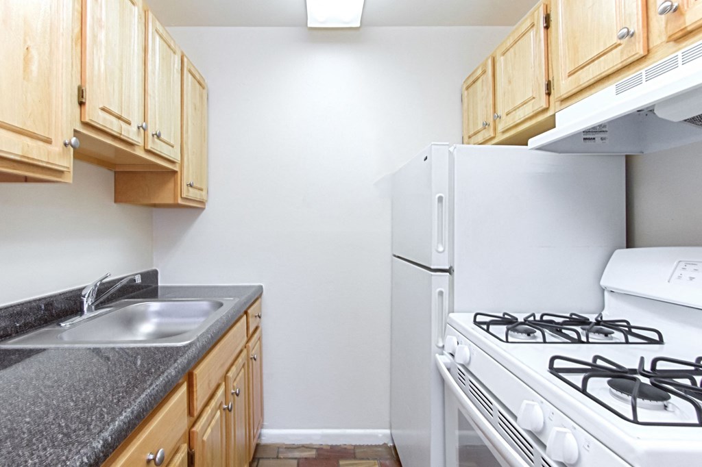 kitchen with white energy efficient appliances, gas stove, and wood cabinetry at fort totten apartments in washington dc