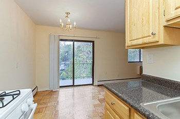 kitchen with wood cabinetry, energy efficient appliances and view of dining area and balcony at fort totten apartments in washington dc - Photo Gallery 5