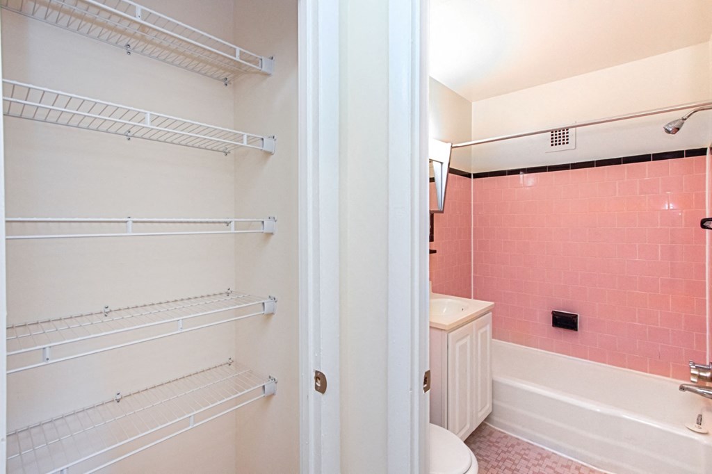 bathroom with tub, vanity, toilet and large linen closet at fort totten apartments in washington dc