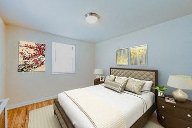 bedroom with bed, night stand, hardwood floor and modern lighting at garden village tax credit apartments in congress heights washington dc
