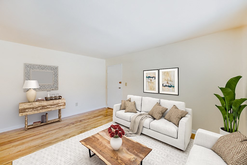 a living room with a white couch and a wooden coffee table at garden village tax credit apartments in congress heights washington dc