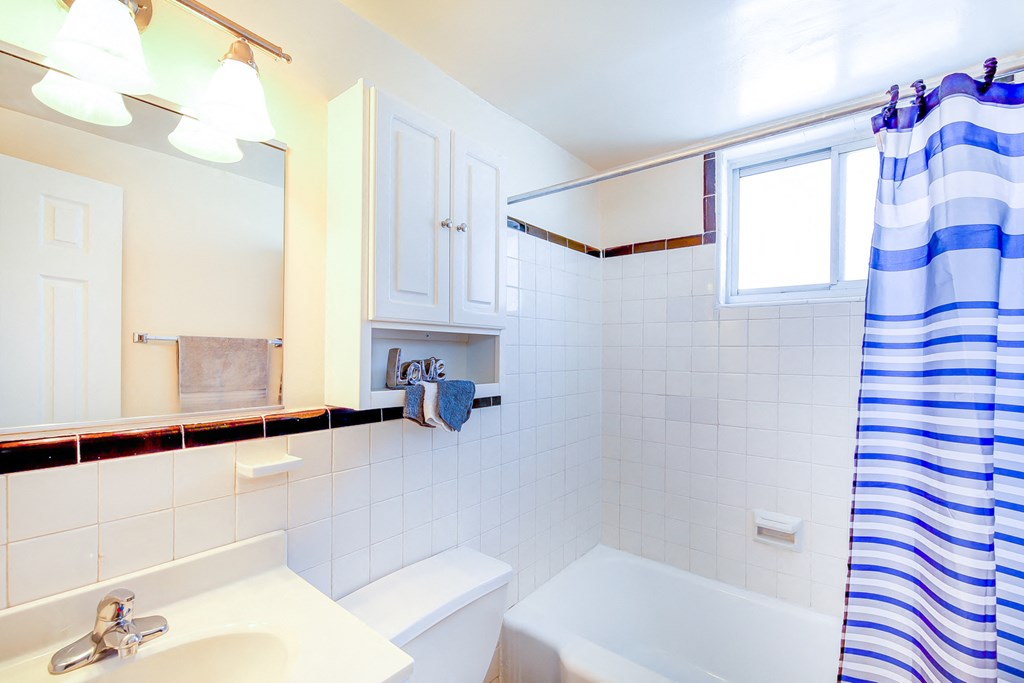 bathroom with tub, toilet, mirror, vanity and small windows at garden village tax credit apartments in congress heights washington dc