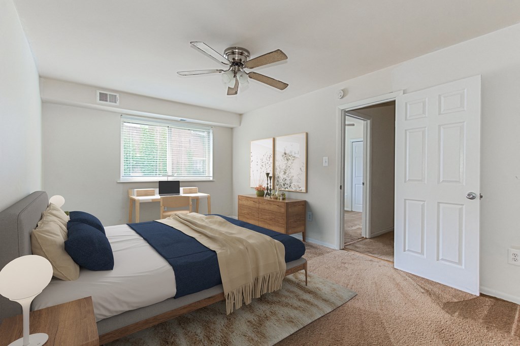 a bedroom with a bed and a ceiling fan and a door to a bathroom at halley house apartments in washington dc