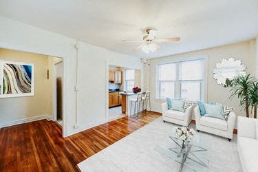living area with sofa, social seating, large windows, hardwood floors and view of kitchen at hampton courts apartments in washington dc