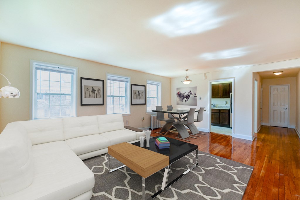 living area with large windows, sofa, coffee table, hardwood floors and view of dining area at hillside terrace apartments in washington dc