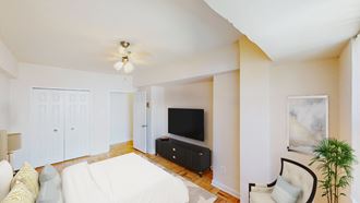 bedroom with bed, tv, dresser, ceiling fan, and sitting area at hilltop house apartments in columbia heights washington dc