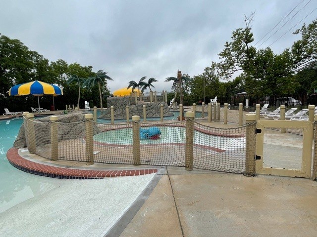 A pool area with a fence and a water slide.