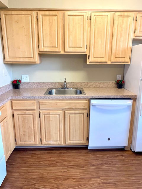 A kitchen with wooden cabinets and a white dishwasher.