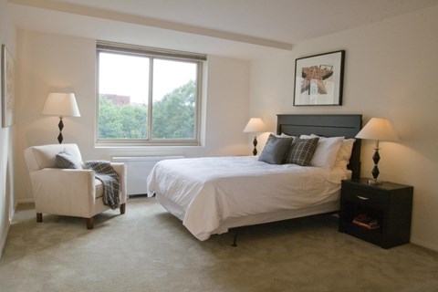 A bedroom with a large bed, a chair, and two lamps.