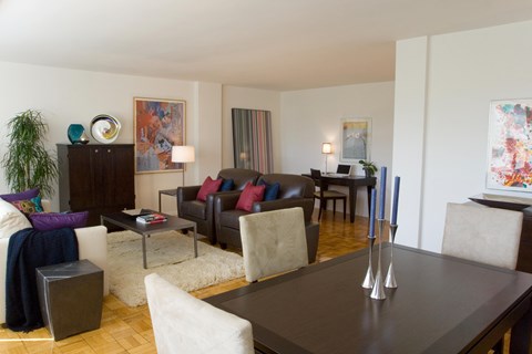 A living room with a brown table and white chairs.