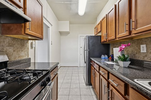 A kitchen with a black refrigerator and wooden cabinets.