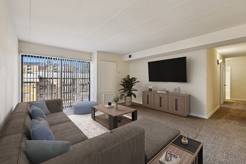 A living room with a grey couch and a flat screen TV mounted on the wall.