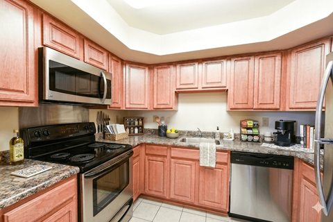 A kitchen with pink cabinets and stainless steel appliances.