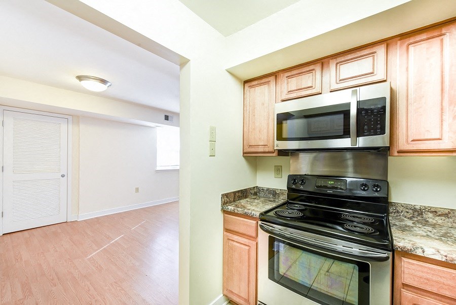 kitchen with stainless steel appliances and view of living area with wood flooring at jasper place apartments in congress heights washington dc