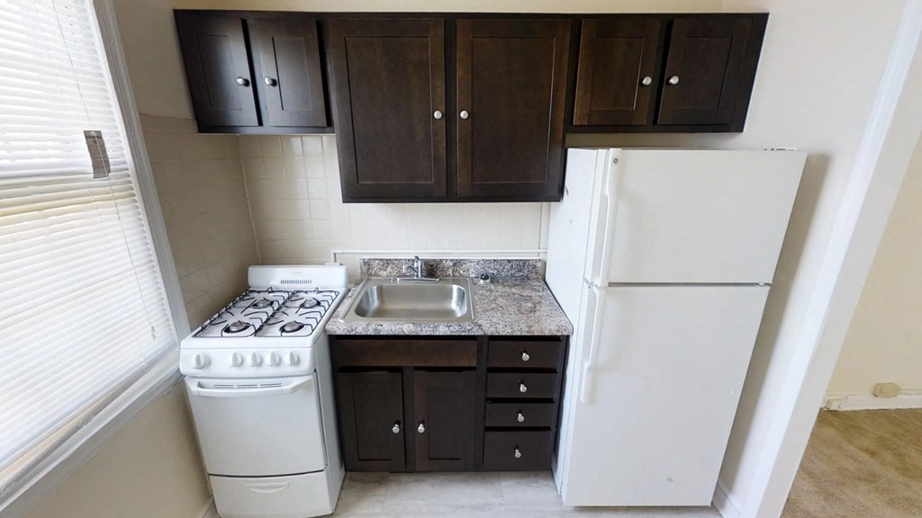 A kitchen with a white stove and refrigerator, and dark brown cabinets.
