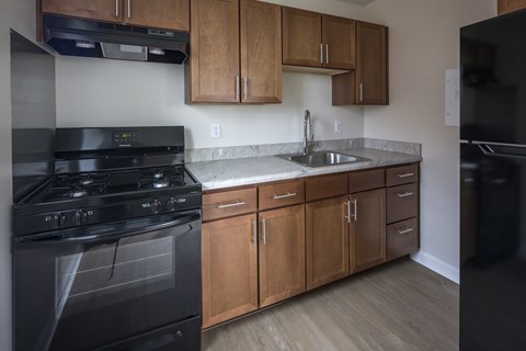 A kitchen with a black stove top oven and wooden cabinets.