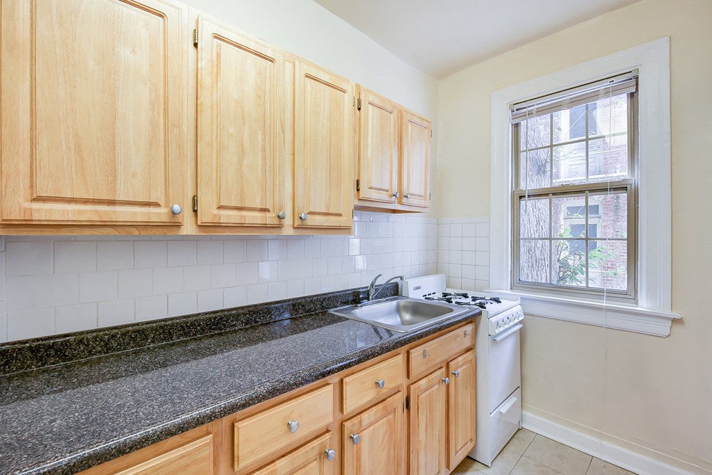 kitchen with tile floorings, wood cabinetry, refrigerator and gas range at 3151 mount pleasant apartments in washington dc