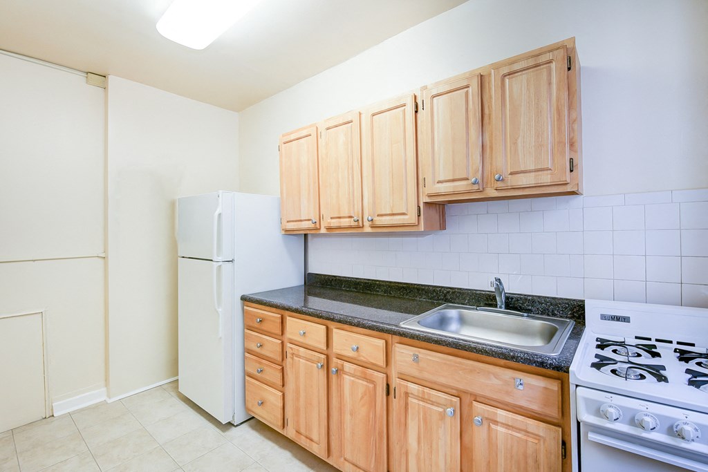kitchen with tile floorings, wood cabinetry, refrigerator and gas range at 3151 mount pleasant apartments in washington dc