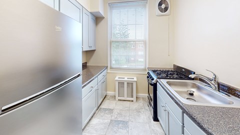 A kitchen with a stainless steel refrigerator and a granite countertop.