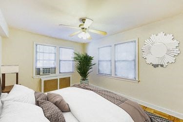 bedroom with bed, large windows, hardwood flooring and ceiling fan at meridian park apartments in washington dc
