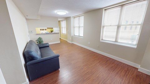 A living room with a blue couch and wooden floors.