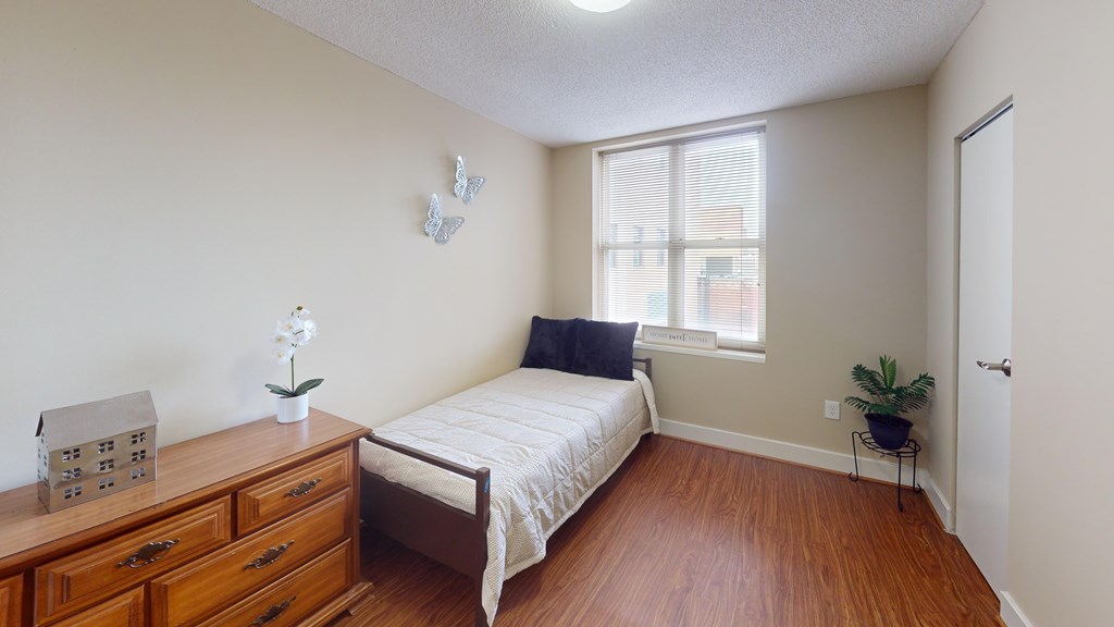 A bedroom with a bed, dresser, and a window.
