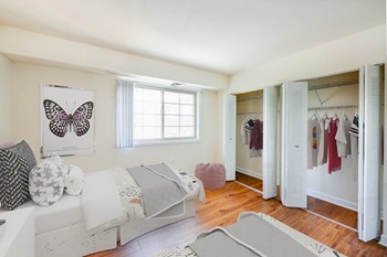 bedroom with two full sized beds, hardwood flooring, window and large closets at naylor overlook apartments in washington dc - Photo Gallery 4
