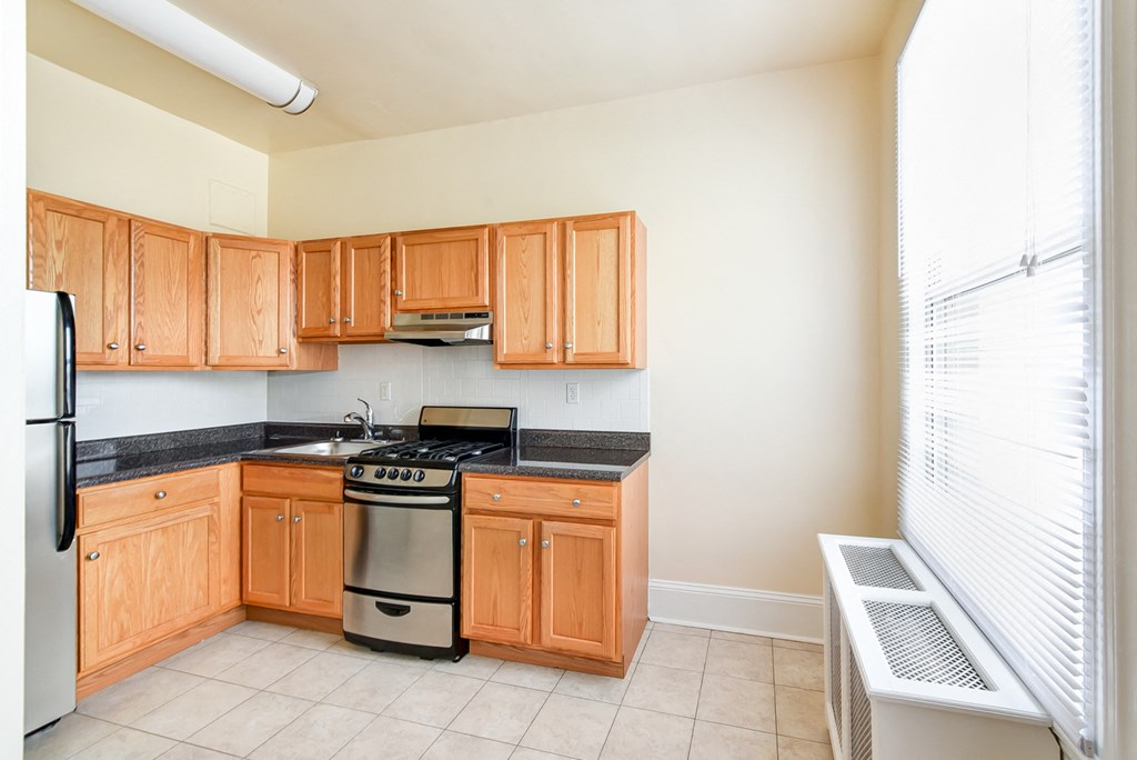 kitchen with stainless steel appliances, wood cabinetry and large window at norwood apartments in washington dc