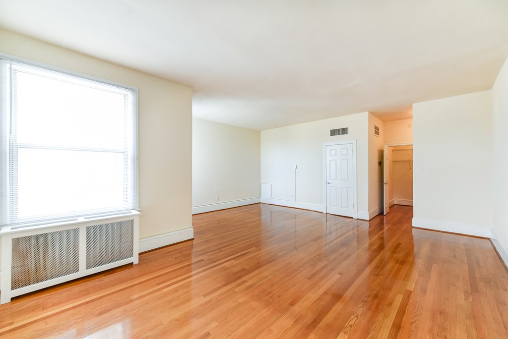 vacant living area with hardwood flooring and large windows at norwood apartments in washington dc
