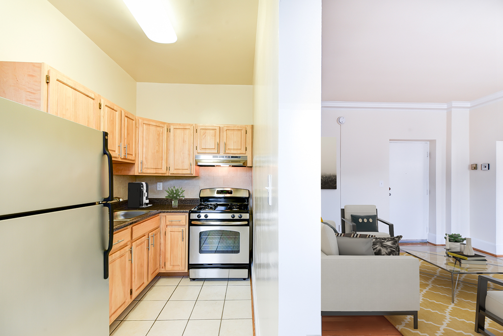 kitchen with stainless steel appliances, wood cabinetry and view of living area at norwood apartments in washington dc