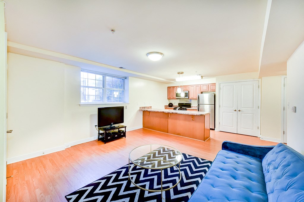 living area with sofa, credenza, tv, coffee table, window, and view of large open kitchen at park vista apartments in washington dc