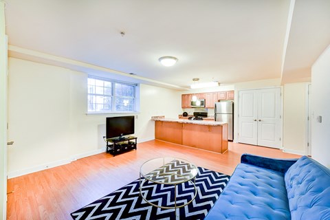 living area with sofa, credenza, tv, coffee table, window, and view of large open kitchen at park vista apartments in washington dc