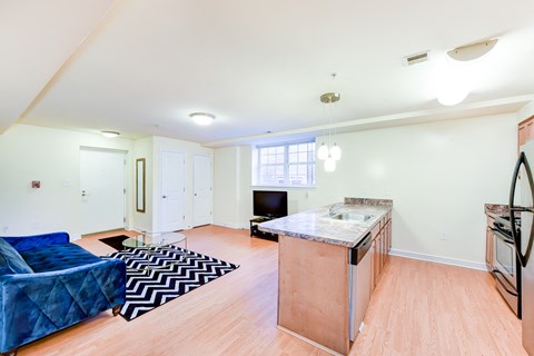 living area with sofa, coffee table, hardwood flooring and view of kitchen with large island at park vista apartments in washington dc