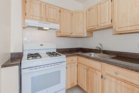 a kitchen with wooden cabinets and a stove top oven and a sink