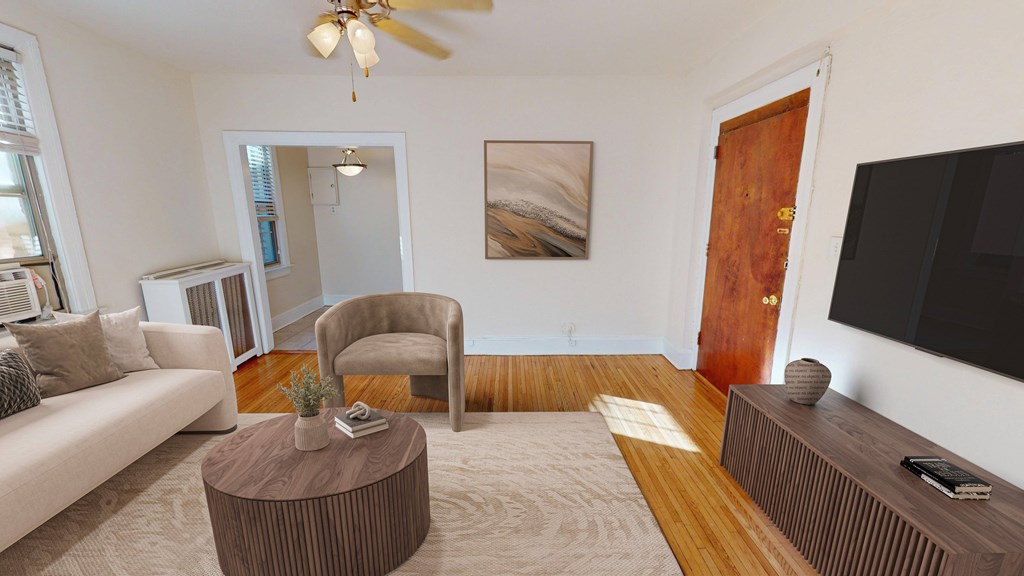A living room with a white couch, a brown armchair, a coffee table, and a flat-screen TV.