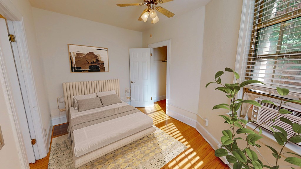 A bedroom with a bed, a ceiling fan, and a plant.