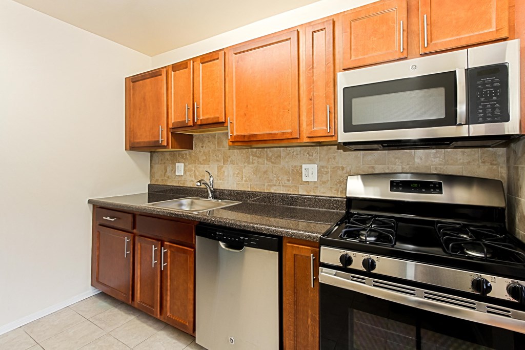 a kitchen with stainless steel appliances and wooden cabinets at penn view apartments in washington dc