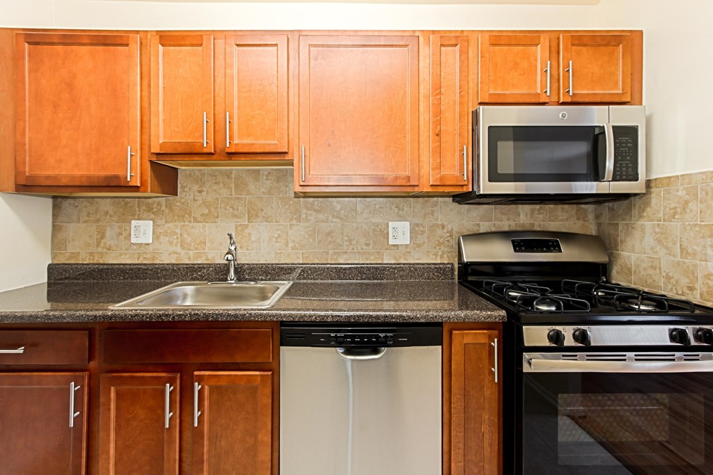 a kitchen with wooden cabinets and a sink and a stove at penn view apartments in washington dc