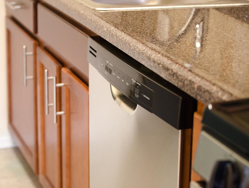 a dishwasher in a kitchen with a granite counter top at penn view apartments in washington dc