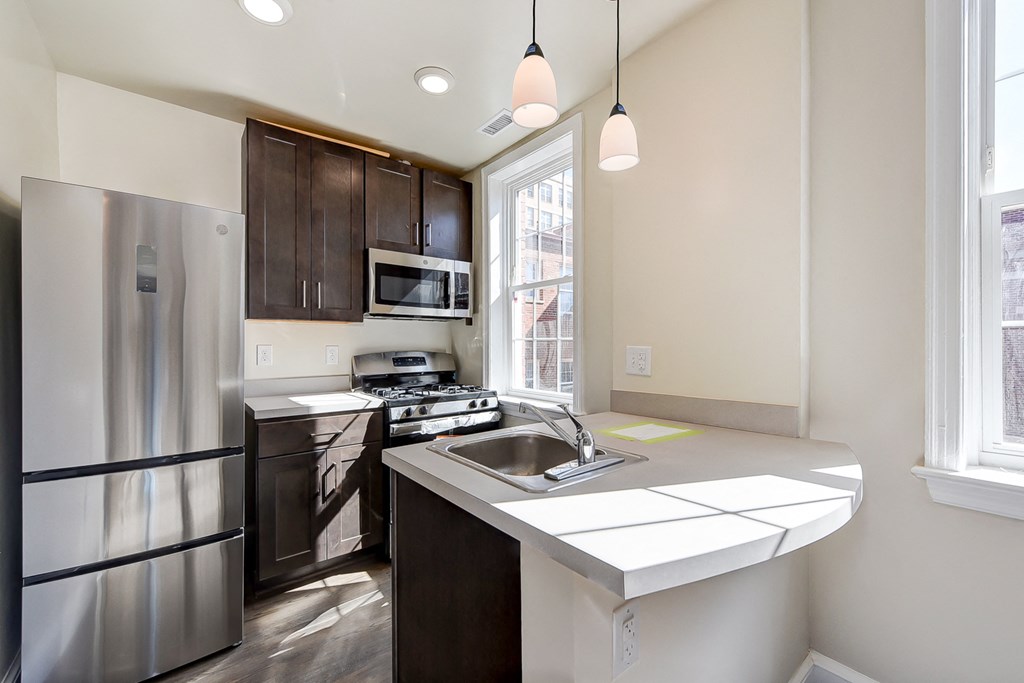 kitchen with espresso cabinetry, breakfast bar and stainless steel appliances at petworth station apartments in washington dc