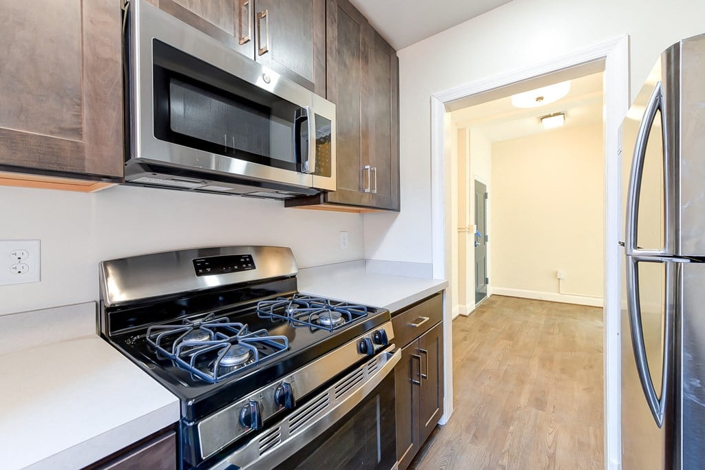 kitchen with espresso cabinetry, view of dining area and stainless steel appliances at petworth station apartments in washington dc