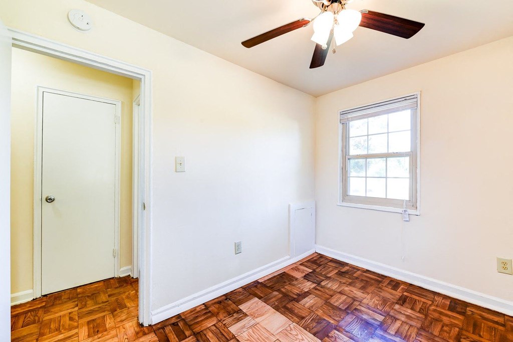 vacant bedroom with hardwood flooring, ceiling fan, window and view of hallway at richman apartments in Washington dc