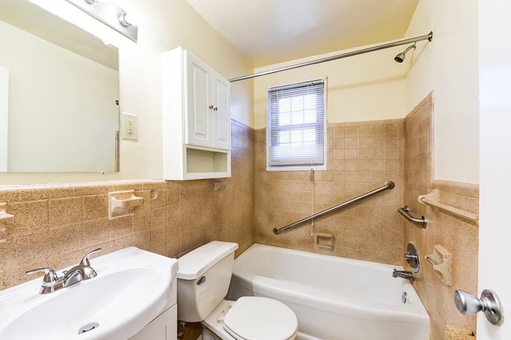bathroom with vanity, toilet, tub and large mirror at richman apartments in washington dc