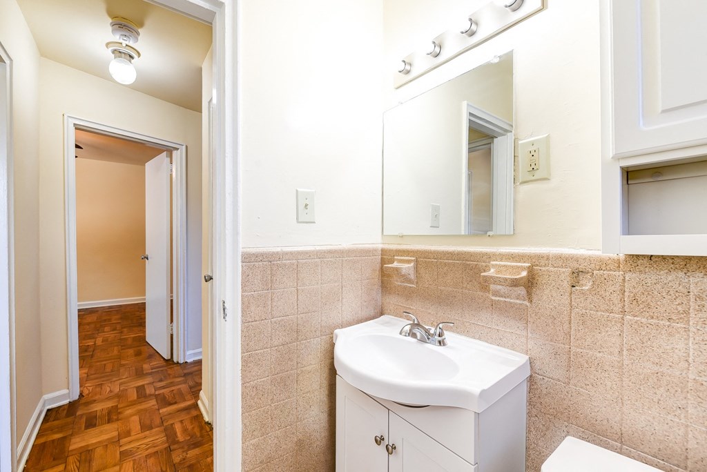 bathroom with vanity, toilet, tub and large mirror at richman apartments in washington dc